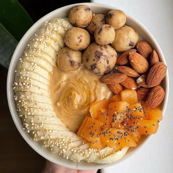 A simple bowl of oatmeal with lots of banana slices, nuts, and fruits.