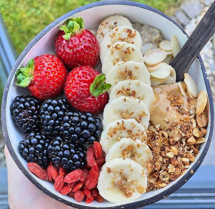 Oatmeal preparation with a mind-blowing topping that includes strawberry, blueberry, banana slices, and nuts. 