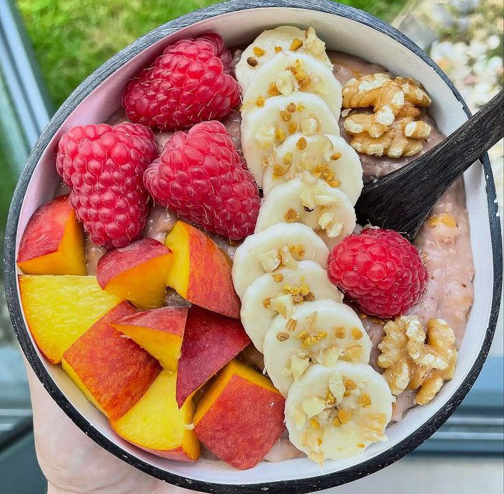 A bowl of oatmeal, strawberry, banana slices, and apple.